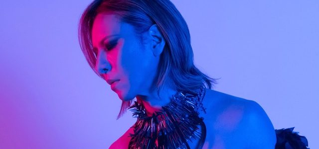 Japanese Artist YOSHIKI cast in blue and pink lighting.